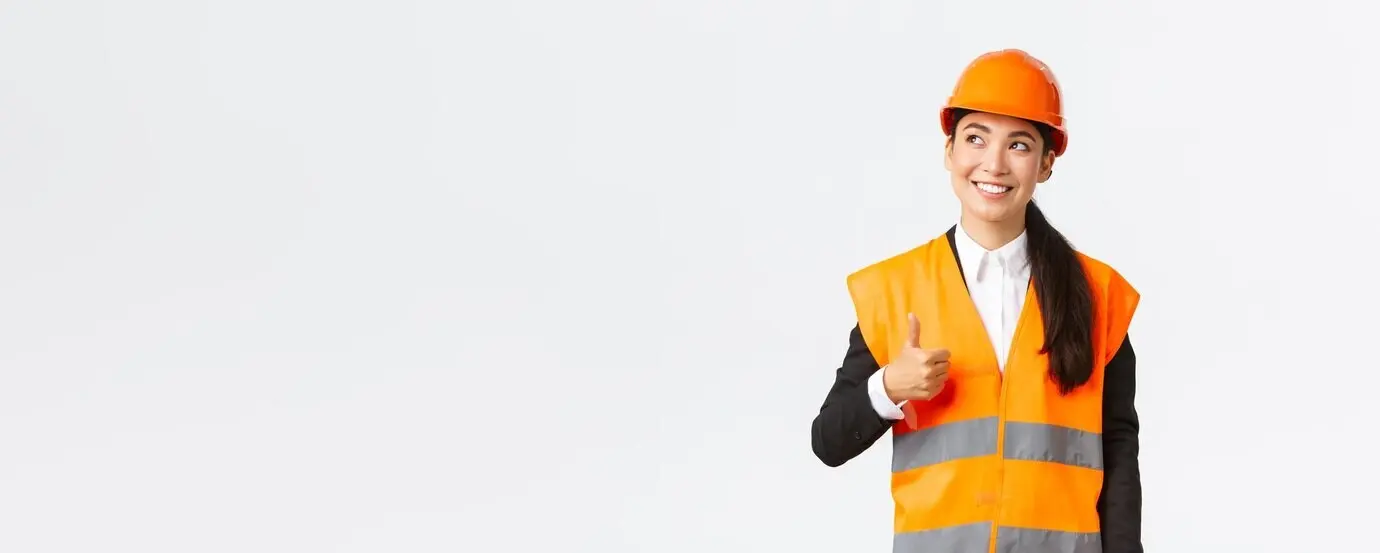 Arquitecta asiática feliz, sonriente y satisfecha con el trabajo de construcción, de pie con casco de seguridad.